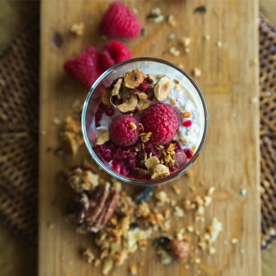 Delicious looking bowl of porridge, fruit and nuts on wood board