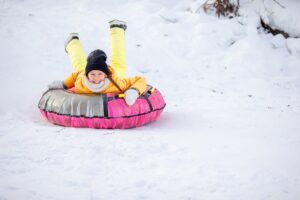 Young girl in an inflatable snow tube slides down snowy hillside