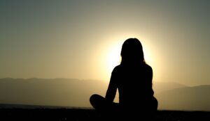 Woman meditating at sunrise